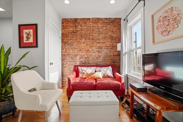 sitting room featuring light hardwood / wood-style floors and brick wall