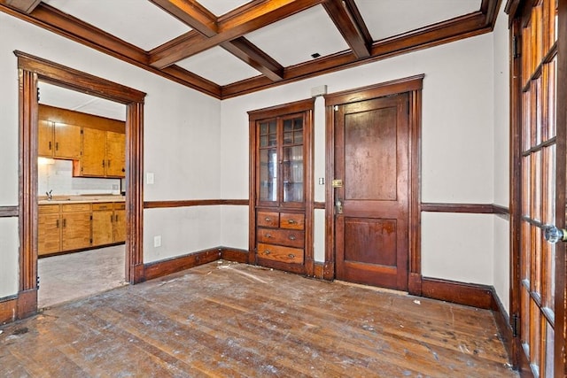 empty room featuring coffered ceiling, crown molding, hardwood / wood-style flooring, baseboards, and beamed ceiling