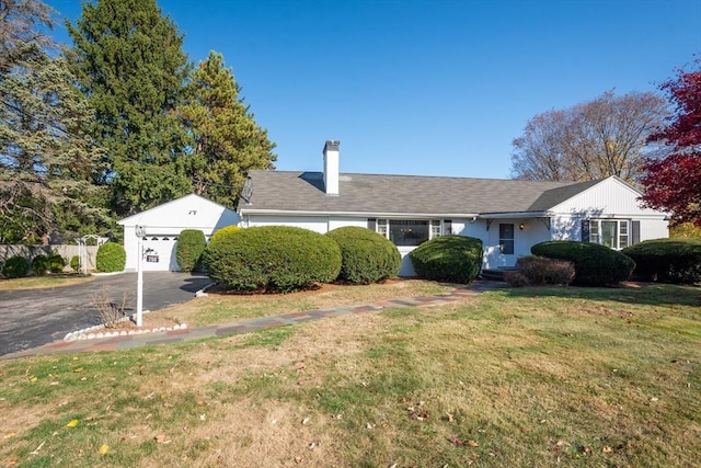 ranch-style house with a garage, a chimney, and a front yard