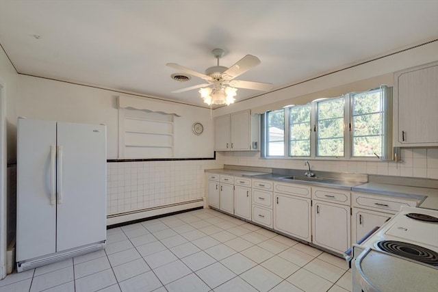 kitchen with white appliances, white cabinets, a ceiling fan, a baseboard heating unit, and a sink