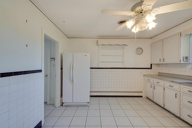 kitchen with visible vents, a baseboard heating unit, tile walls, and freestanding refrigerator