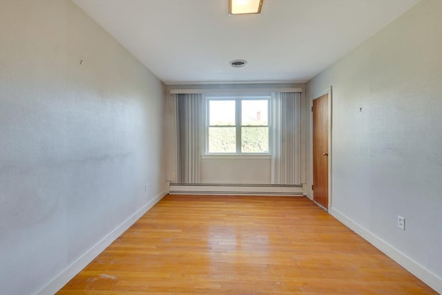 unfurnished room featuring a baseboard heating unit, baseboards, visible vents, and light wood finished floors