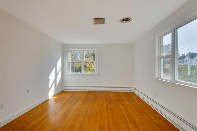 spare room with visible vents, baseboards, a baseboard radiator, light wood-style flooring, and a baseboard heating unit