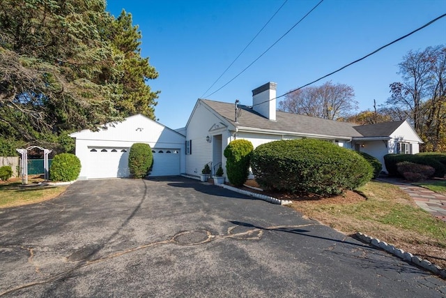 view of side of property featuring a garage, aphalt driveway, and a chimney