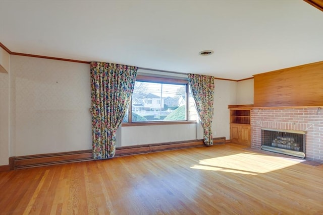 unfurnished living room with visible vents, ornamental molding, a brick fireplace, wood finished floors, and baseboards