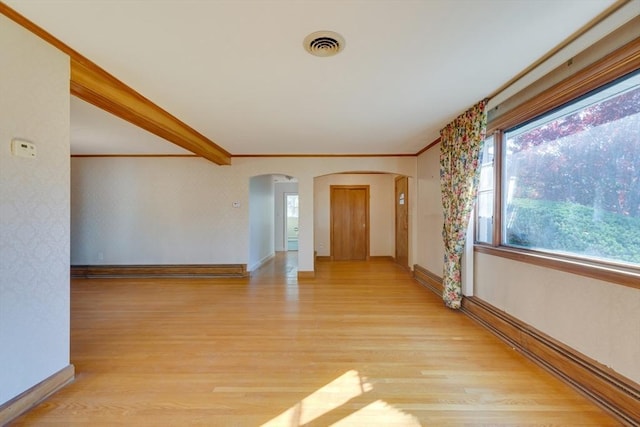 spare room with light wood-type flooring, arched walkways, visible vents, and baseboards