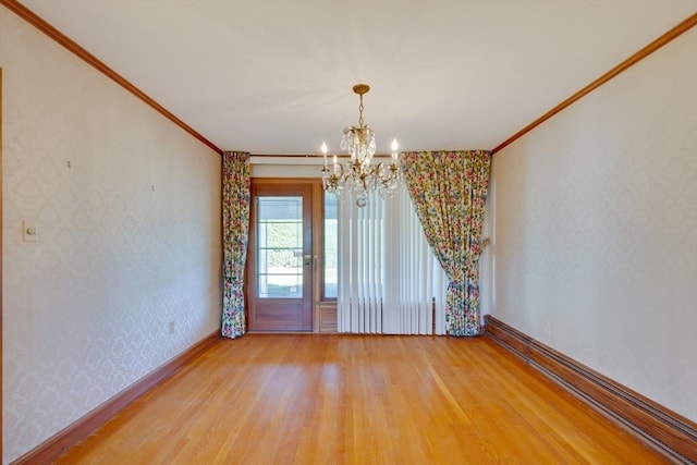 empty room featuring wallpapered walls, crown molding, baseboards, and wood finished floors