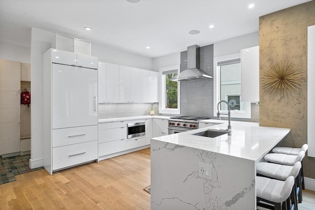 26 Salisbury Rd Unit 26, Newton, MA 02458 - kitchen with wall chimney range hood, a sink, stainless steel appliances, light wood-style floors, and recessed lighting