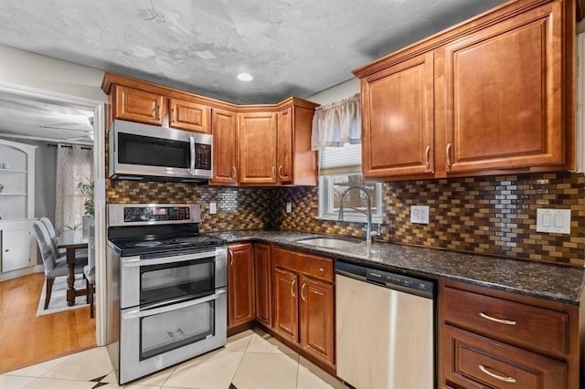 4 Ludington Rd, Worcester, MA 01602 - kitchen with stainless steel appliances, a sink, brown cabinets, dark stone counters, and backsplash