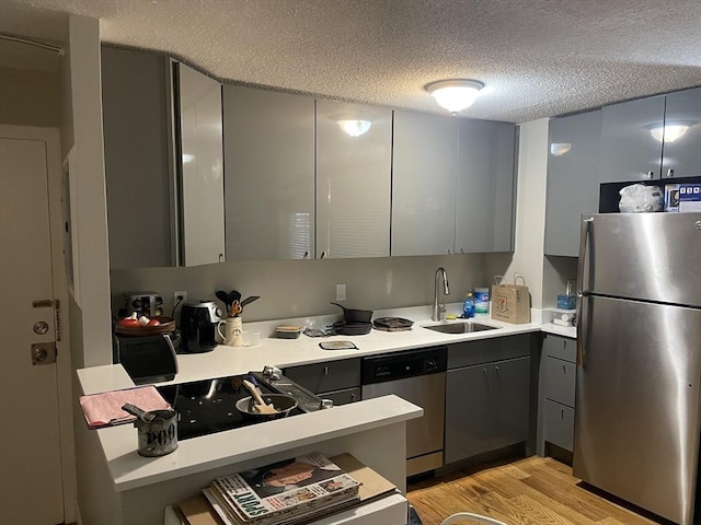 kitchen featuring sink, stainless steel appliances, light hardwood / wood-style flooring, a textured ceiling, and gray cabinets