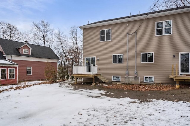 snow covered rear of property with a wooden deck