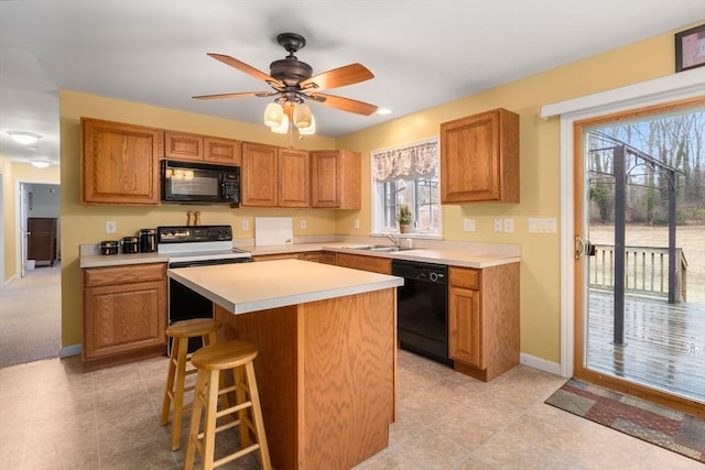 kitchen with black appliances, a sink, light countertops, and a center island