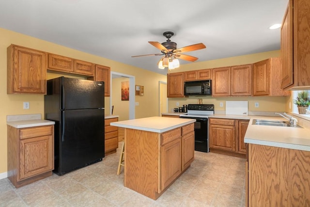 kitchen featuring a ceiling fan, a center island, light countertops, black appliances, and a sink