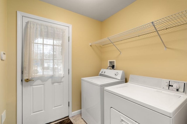 clothes washing area with washing machine and dryer, laundry area, and baseboards