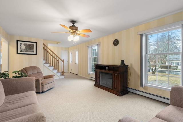 living room featuring stairs, a wealth of natural light, baseboard heating, and wallpapered walls