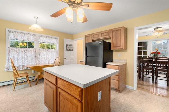 kitchen with a center island, pendant lighting, light countertops, baseboard heating, and freestanding refrigerator