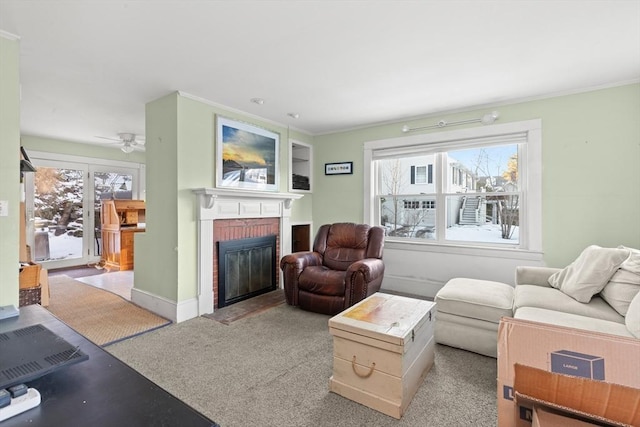 living room featuring light carpet, a fireplace, baseboards, and crown molding