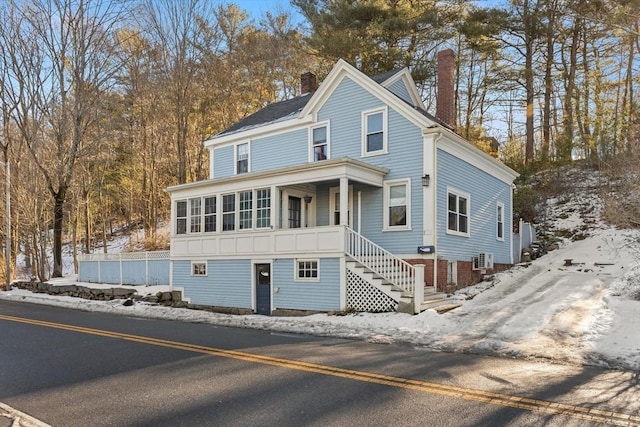 view of front of house with a chimney, central AC unit, and stairs