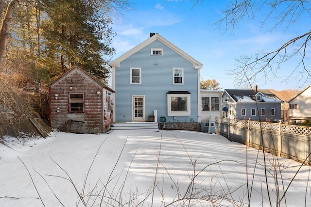 back of house featuring a chimney, fence, and an outdoor structure