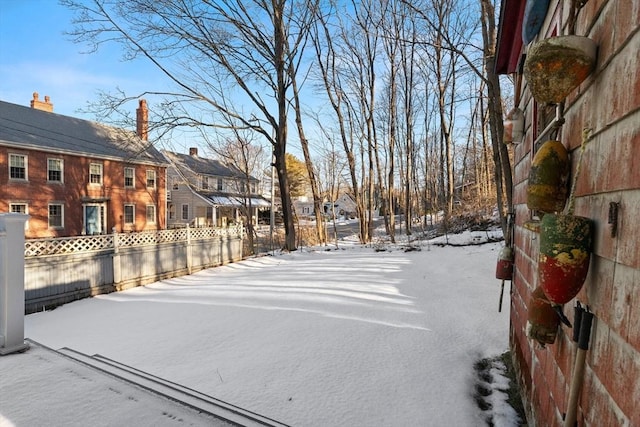 yard covered in snow featuring a residential view and fence