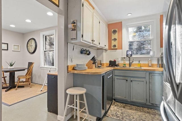 bar with freestanding refrigerator, a sink, and recessed lighting