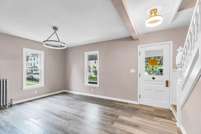 26 Olivine St, Chicopee, MA 01013 - entrance foyer featuring radiator heating unit, wood finished floors, stairway, and beam ceiling