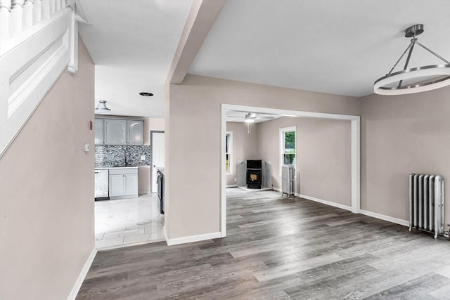 26 Olivine St, Chicopee, MA 01013 - unfurnished living room featuring radiator, a wood stove, wood finished floors, a chandelier, and ceiling fan