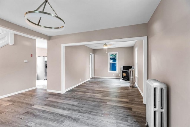 26 Olivine St, Chicopee, MA 01013 - unfurnished living room featuring radiator, a wood stove, wood finished floors, and a ceiling fan