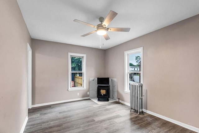26 Olivine St, Chicopee, MA 01013 - unfurnished living room with wood finished floors, ceiling fan, and a wood stove