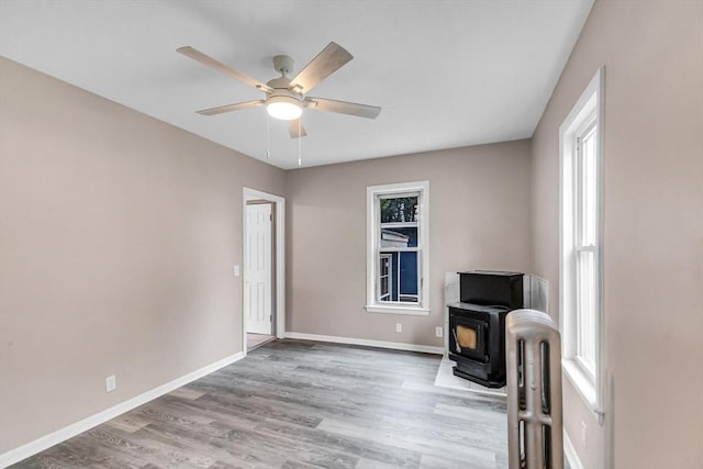 26 Olivine St, Chicopee, MA 01013 - unfurnished living room with a wood stove, wood finished floors, ceiling fan, and radiator heating unit