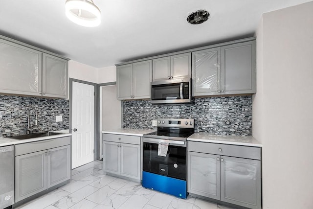 26 Olivine St, Chicopee, MA 01013 - kitchen with appliances with stainless steel finishes, gray cabinetry, light countertops, backsplash, and light marble finish flooring