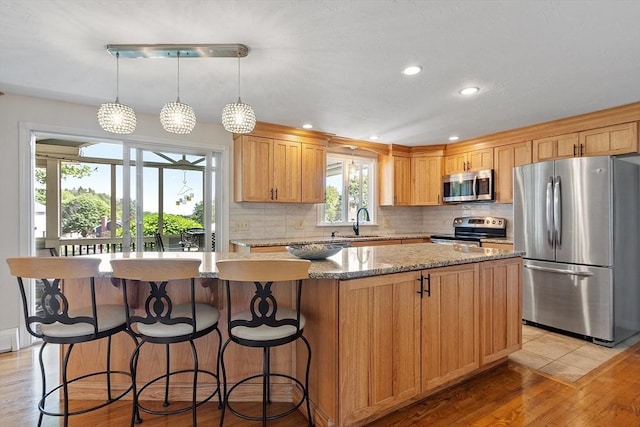 3 Sycamore Dr, Rutland, MA 01543 - kitchen with stainless steel appliances, a center island, light wood-style flooring, backsplash, and light stone countertops