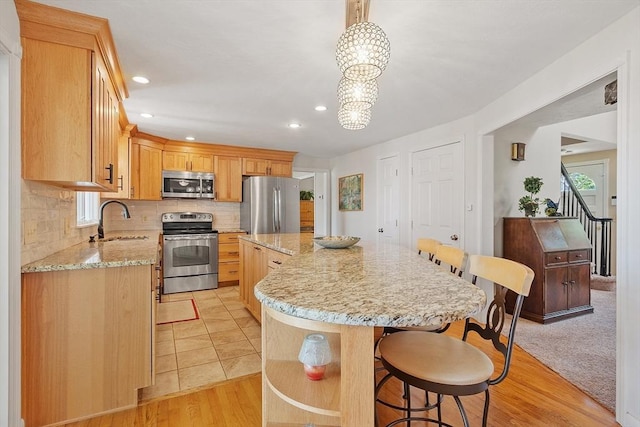 3 Sycamore Dr, Rutland, MA 01543 - kitchen featuring appliances with stainless steel finishes, a center island, decorative backsplash, a breakfast bar area, and light stone countertops