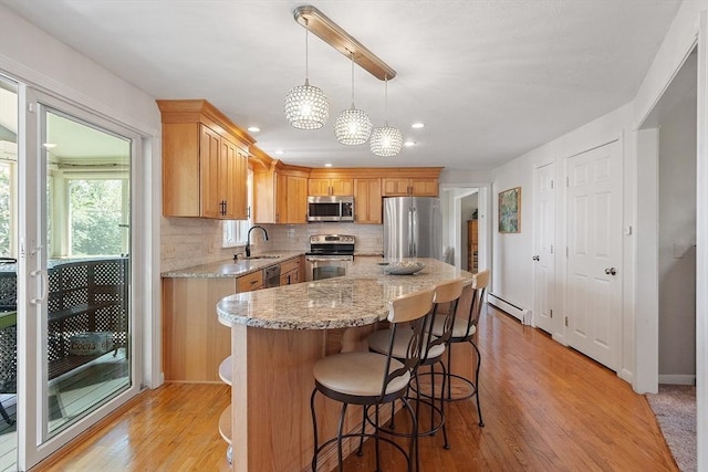 3 Sycamore Dr, Rutland, MA 01543 - kitchen with appliances with stainless steel finishes, baseboard heating, light wood-style flooring, backsplash, and a kitchen bar