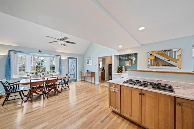 kitchen with light wood-type flooring, light countertops, stainless steel gas stovetop, and vaulted ceiling