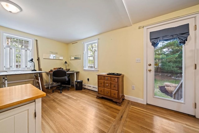 home office with a baseboard heating unit, light wood finished floors, and baseboard heating
