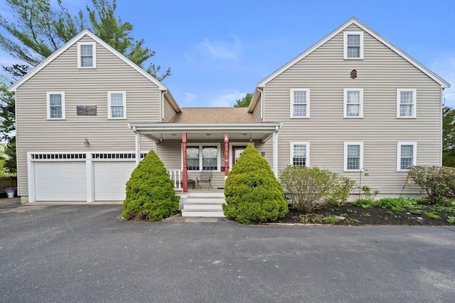 view of front of property featuring aphalt driveway, a porch, and a garage