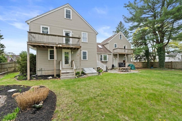rear view of property featuring a fenced backyard, a balcony, and a lawn