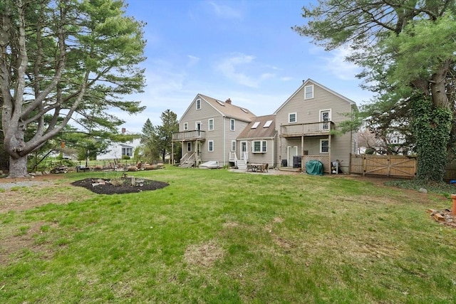rear view of house featuring a gate, fence, entry steps, and a lawn