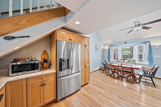kitchen featuring stainless steel appliances, light wood-type flooring, vaulted ceiling, light countertops, and a baseboard radiator