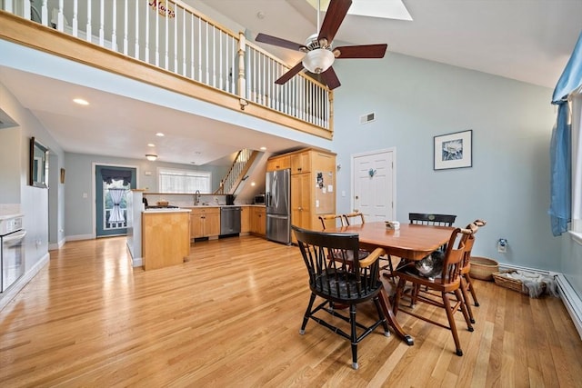 dining room featuring high vaulted ceiling, a ceiling fan, visible vents, light wood-style flooring, and baseboards