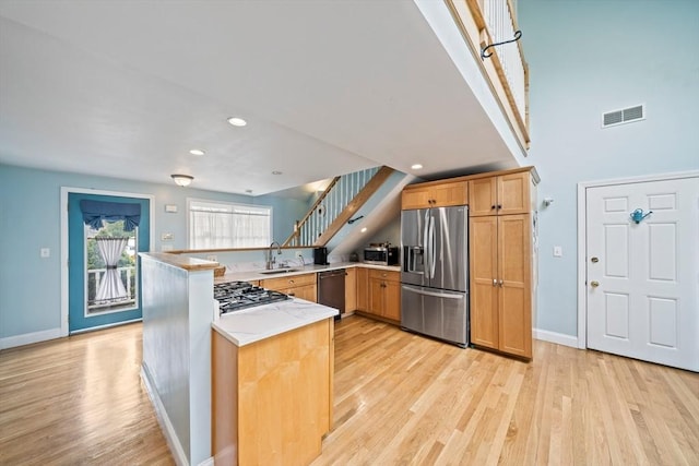 kitchen featuring stainless steel appliances, light wood finished floors, baseboards, visible vents, and a peninsula
