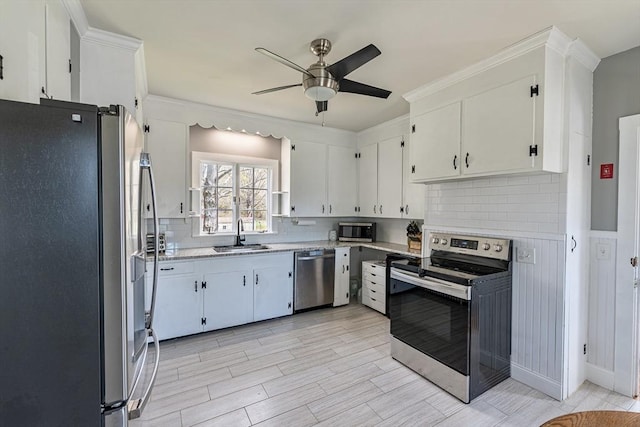 kitchen with tasteful backsplash, white cabinets, a sink, appliances with stainless steel finishes, and ceiling fan