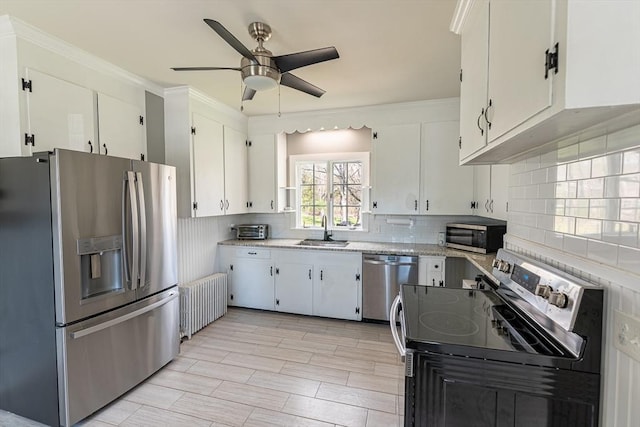 kitchen with a sink, tasteful backsplash, a ceiling fan, radiator heating unit, and appliances with stainless steel finishes