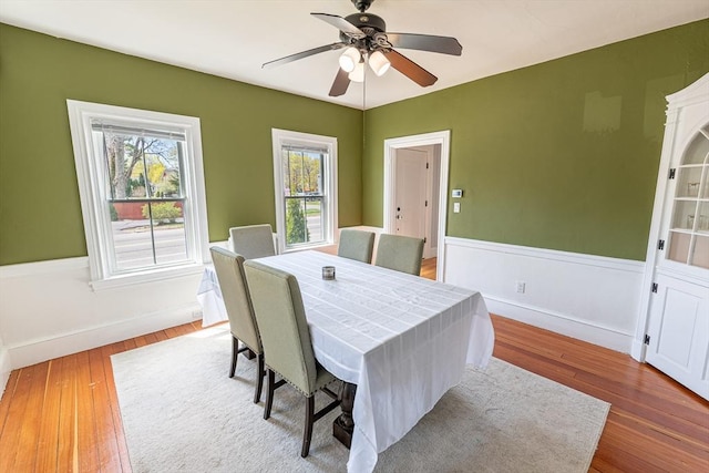 dining space featuring baseboards, wood finished floors, and a ceiling fan