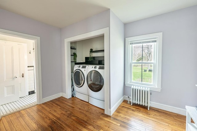 washroom featuring radiator heating unit, hardwood / wood-style flooring, separate washer and dryer, and baseboards