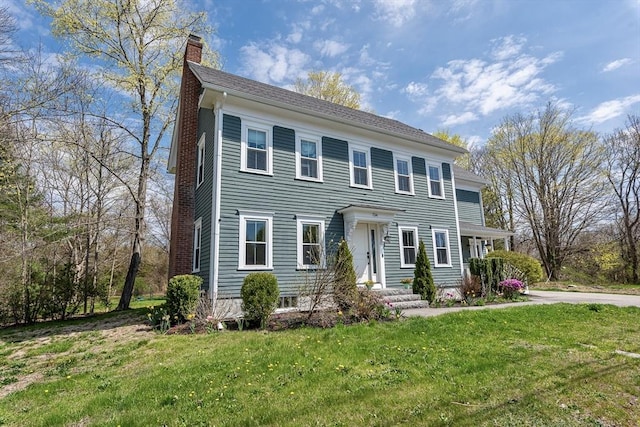 colonial house featuring a front lawn and a chimney