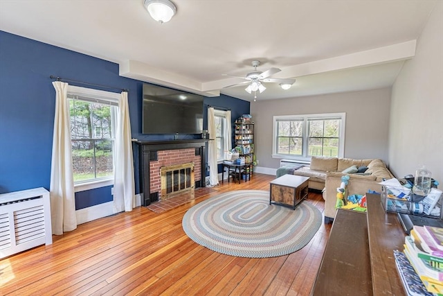 living area with hardwood / wood-style floors, ceiling fan, a wealth of natural light, and baseboards