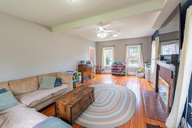 living room with a ceiling fan, baseboards, light wood-style flooring, and a fireplace