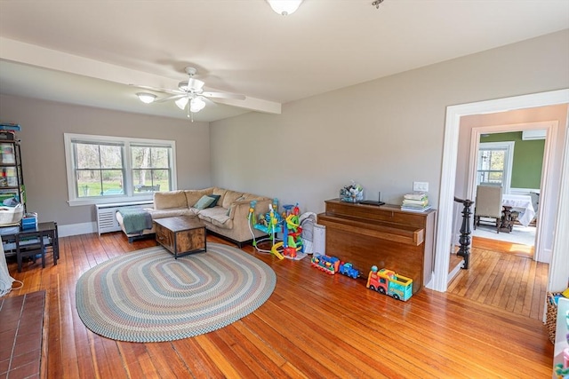 living area with radiator, ceiling fan, hardwood / wood-style floors, and baseboards
